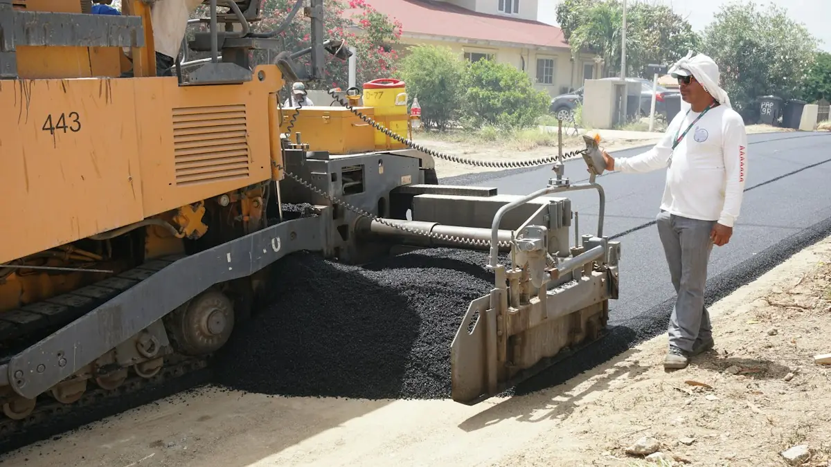 Asphalt paver laying fresh pavement with a worker alongside