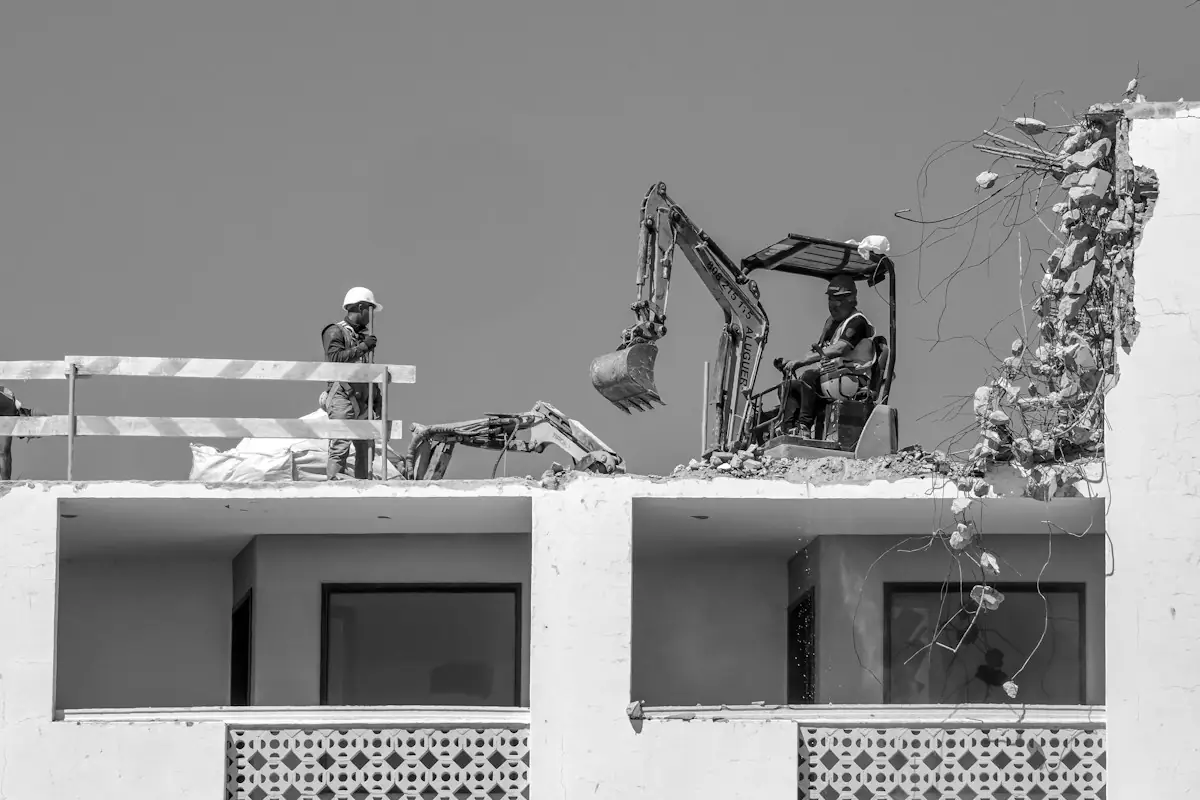 Crew and a mini excavator demolishing part of a building