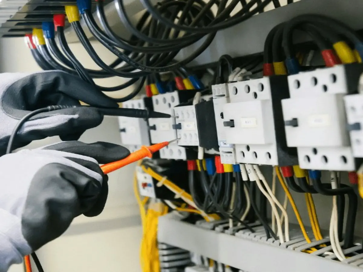 Electrician testing breakers in a distribution panel with a voltage tester