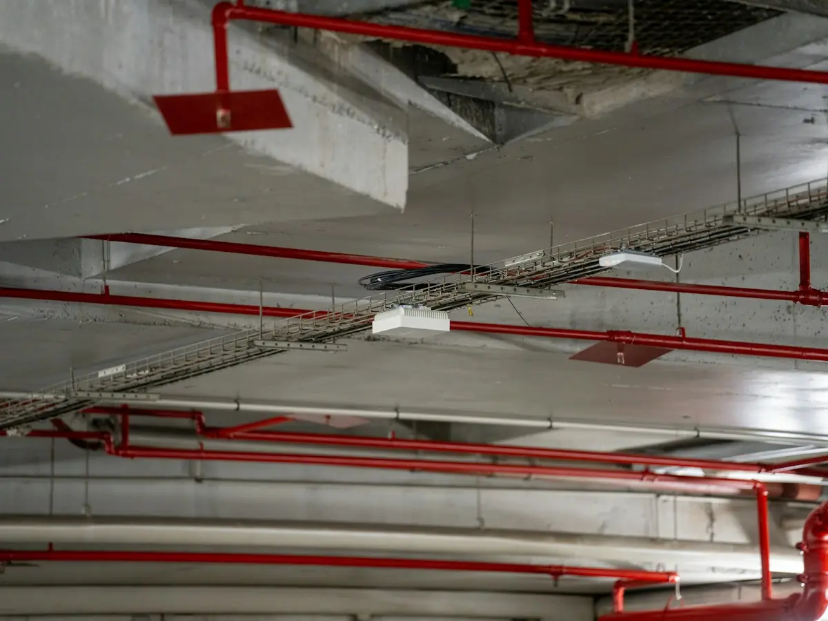 Red fire sprinkler piping running along a concrete parking garage ceiling