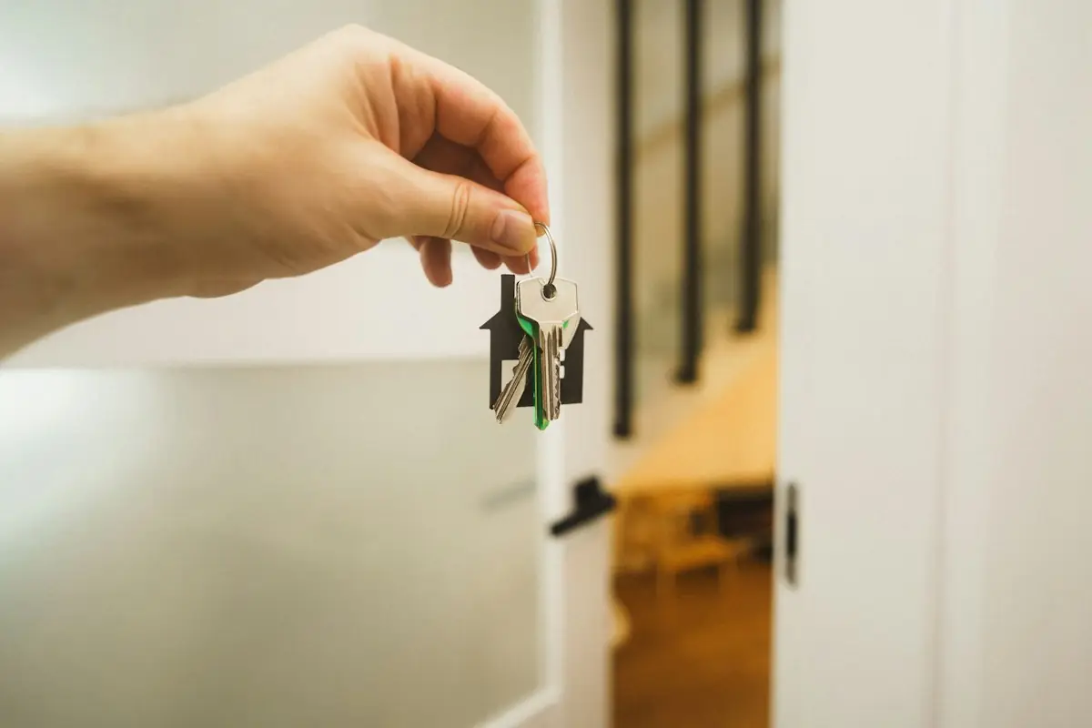 Hand holding a set of keys at an open door