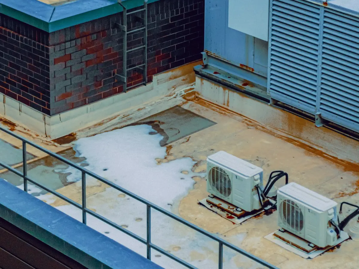 Flat commercial roof with rooftop units and patches of snow