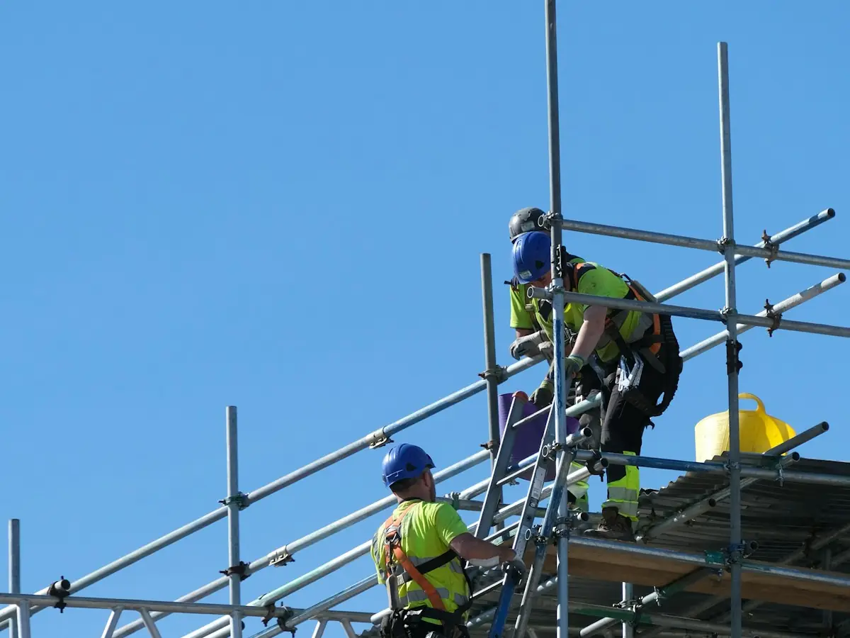 Crew in hard hats and hi-vis climbing scaffolding on a building